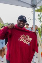 Student smiling and holding a garnet Welcome FSU t-shirt