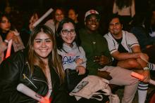 Students sitting together holding FSUnite glow sticks and smiling