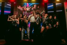 Eleven student performers holding microphones and posing on the Homecoming Live stage 