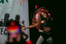 Woman dancing on a stage with arms outstretched at her sides and her hair swirling around her face