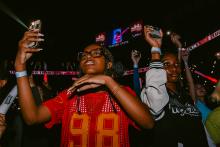 Two students holding their cell phones with the flashlight feature on aloft in a concert crowd